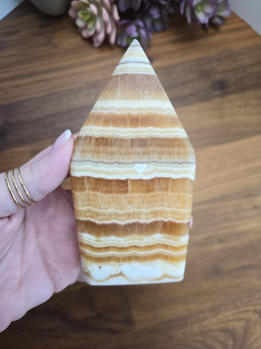 A hand holding a unique, striped, and triangular-shaped object, which appears to be a piece of natural stone or a decorative item.
