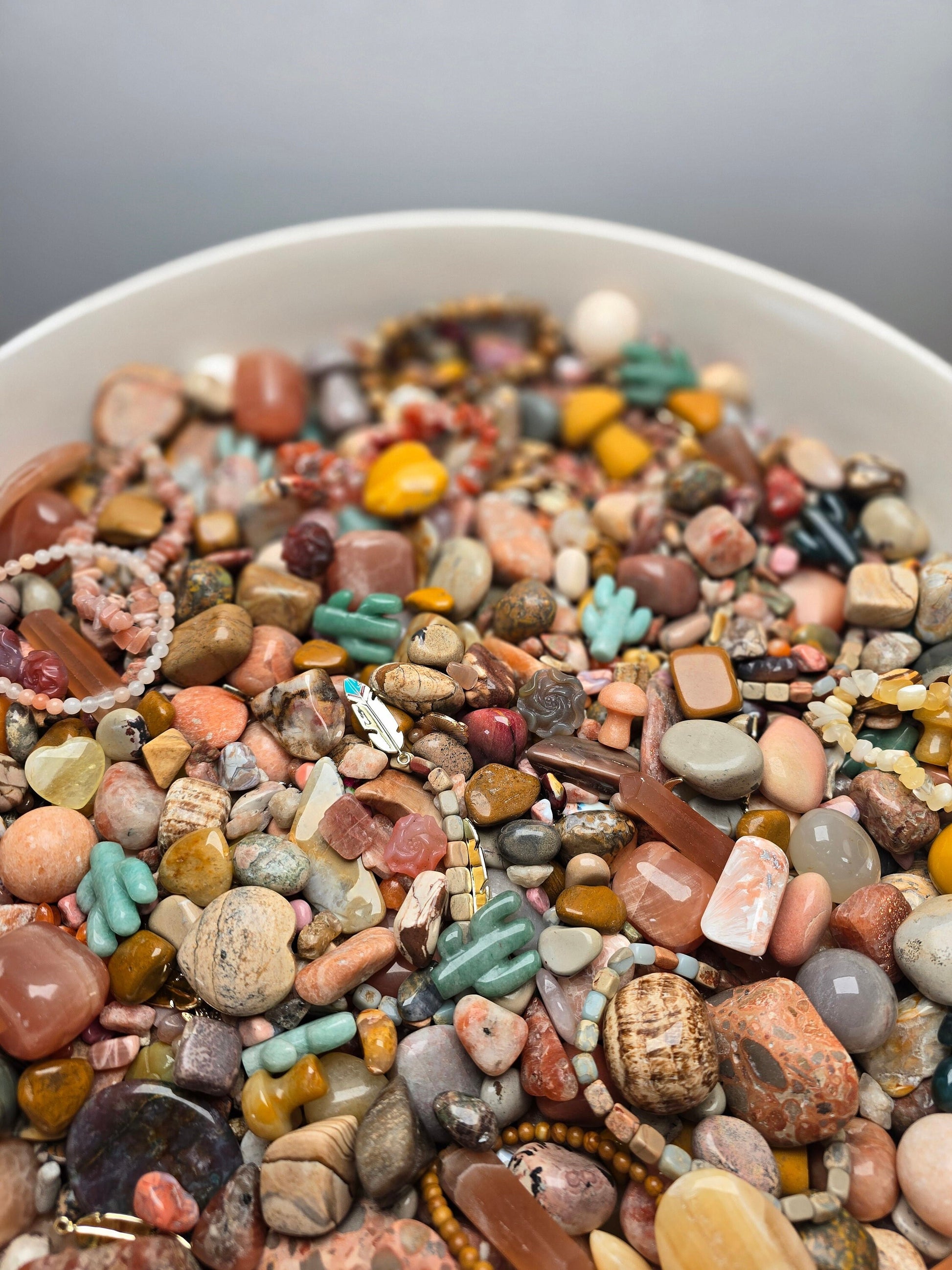 Sedona Sunrise Crystal Confetti is a mix of pink, orange, yellow, and beige you see on a desert hike in the morning. Pops of green aventurine, amazonite, and moss agate crystal cactus carvings and some peach and red like sunset. Earthy granola girl.