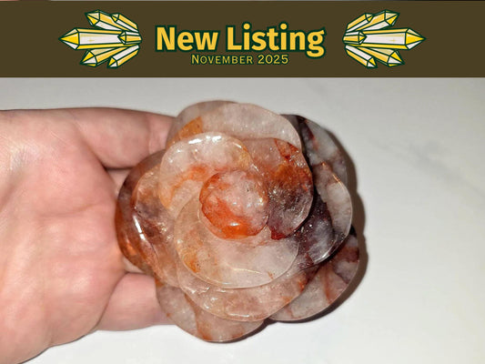 A hand holding a flower-shaped crystal against a white background.