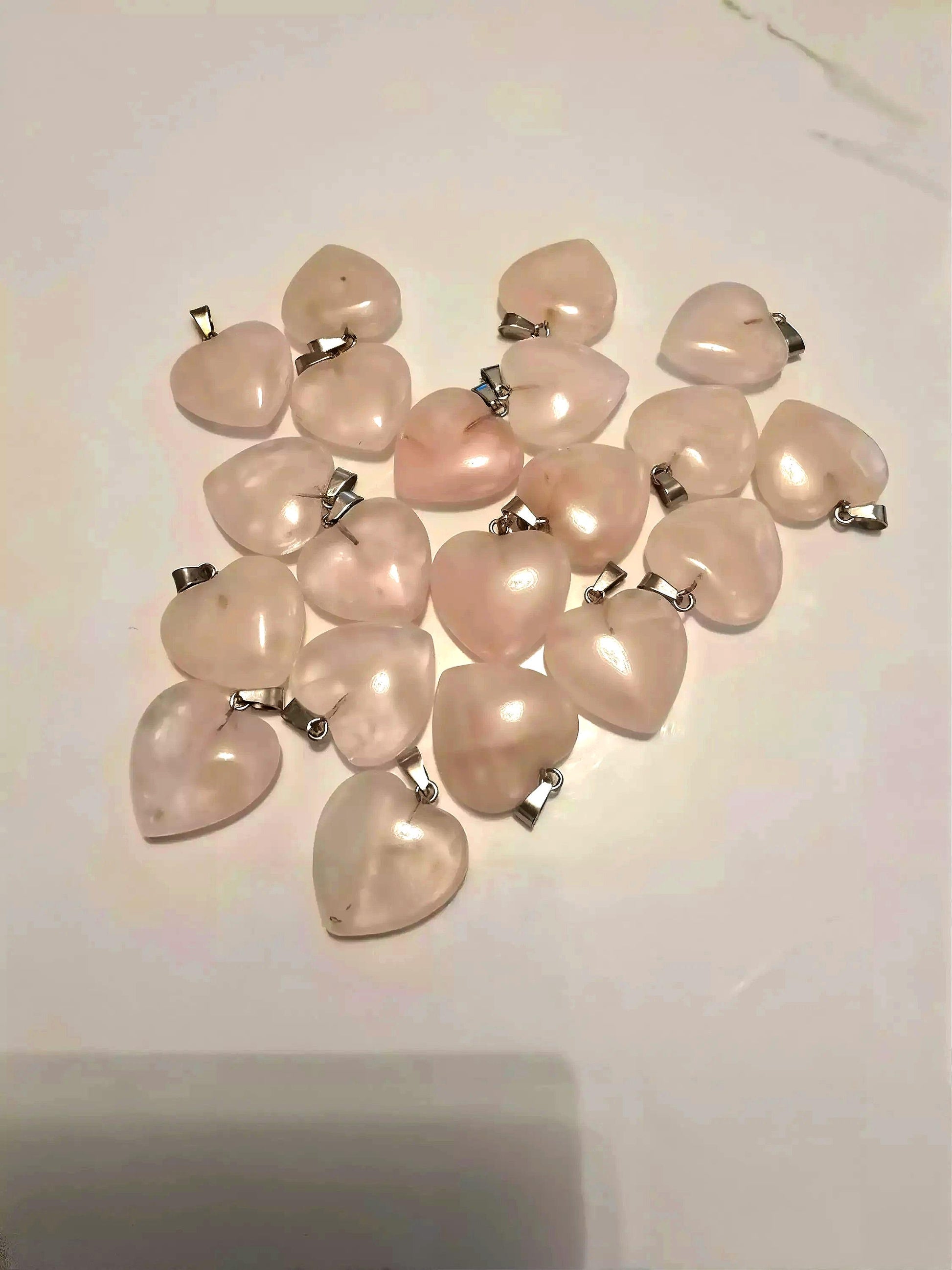 a collection of heart-shaped crystals or stones, some of which are attached to metal pendants.
