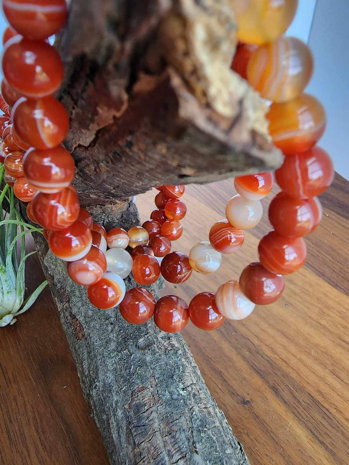 a collection of vibrant red and orange beads arranged in a circular pattern, hanging from a wooden structure.