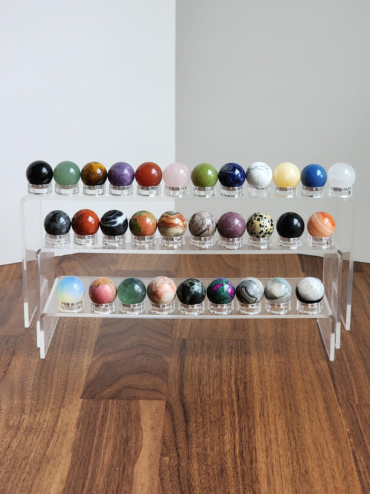 A display of various colorful gemstones and minerals arranged on a clear stand, showcasing their unique shapes and colors.