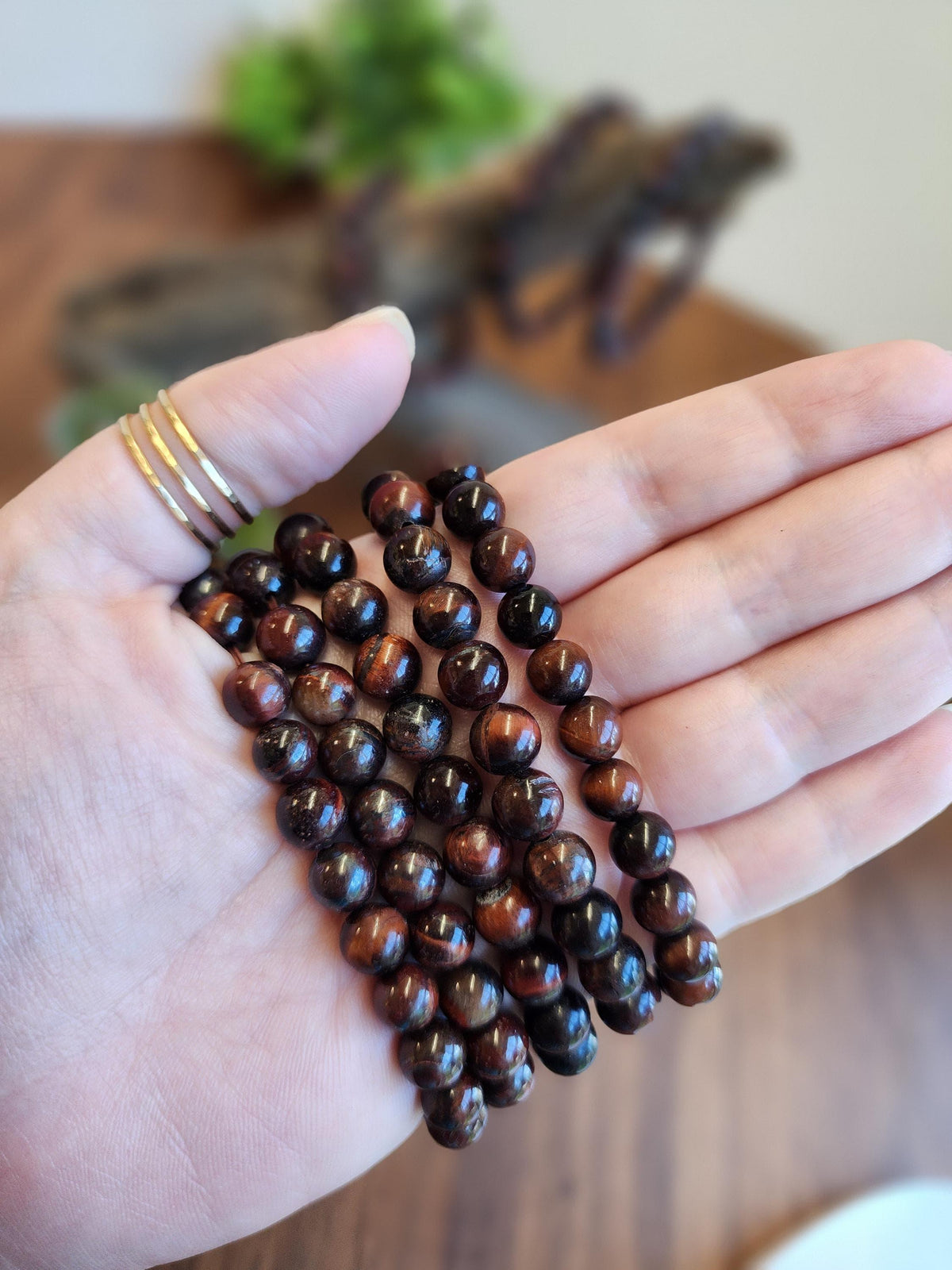 A hand holding a collection of brown and black beaded bracelets.