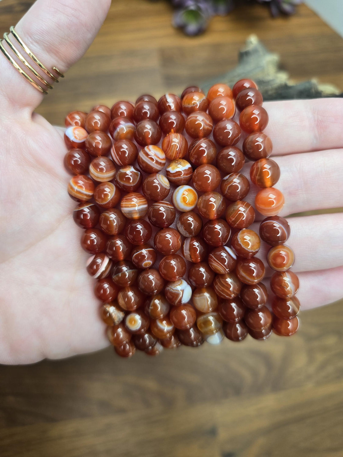 A hand holding a collection of small, round, orange-colored beads.