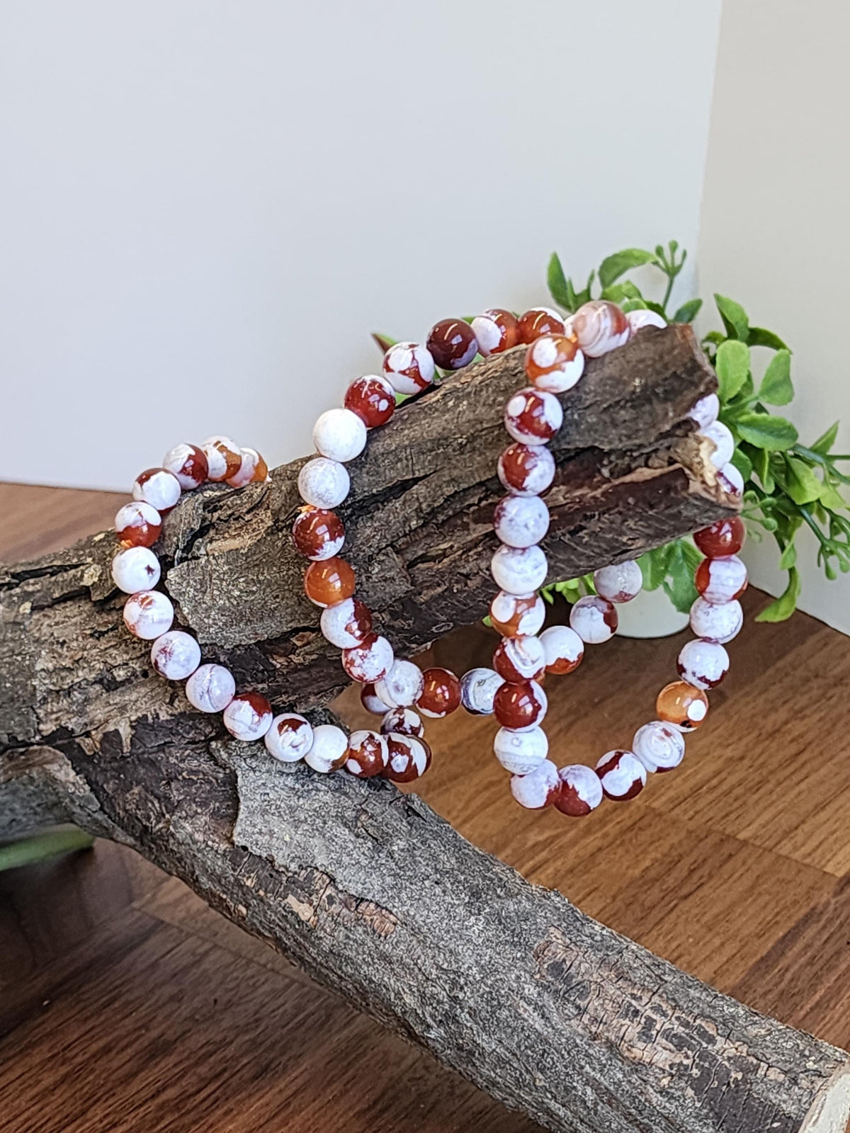 a necklace made of red and white beads, resting on a wooden surface.