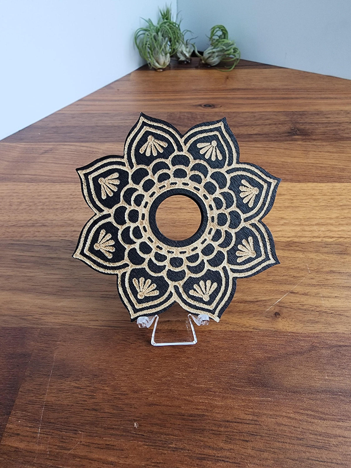a decorative wooden piece with a black and gold floral design, placed on a wooden surface.