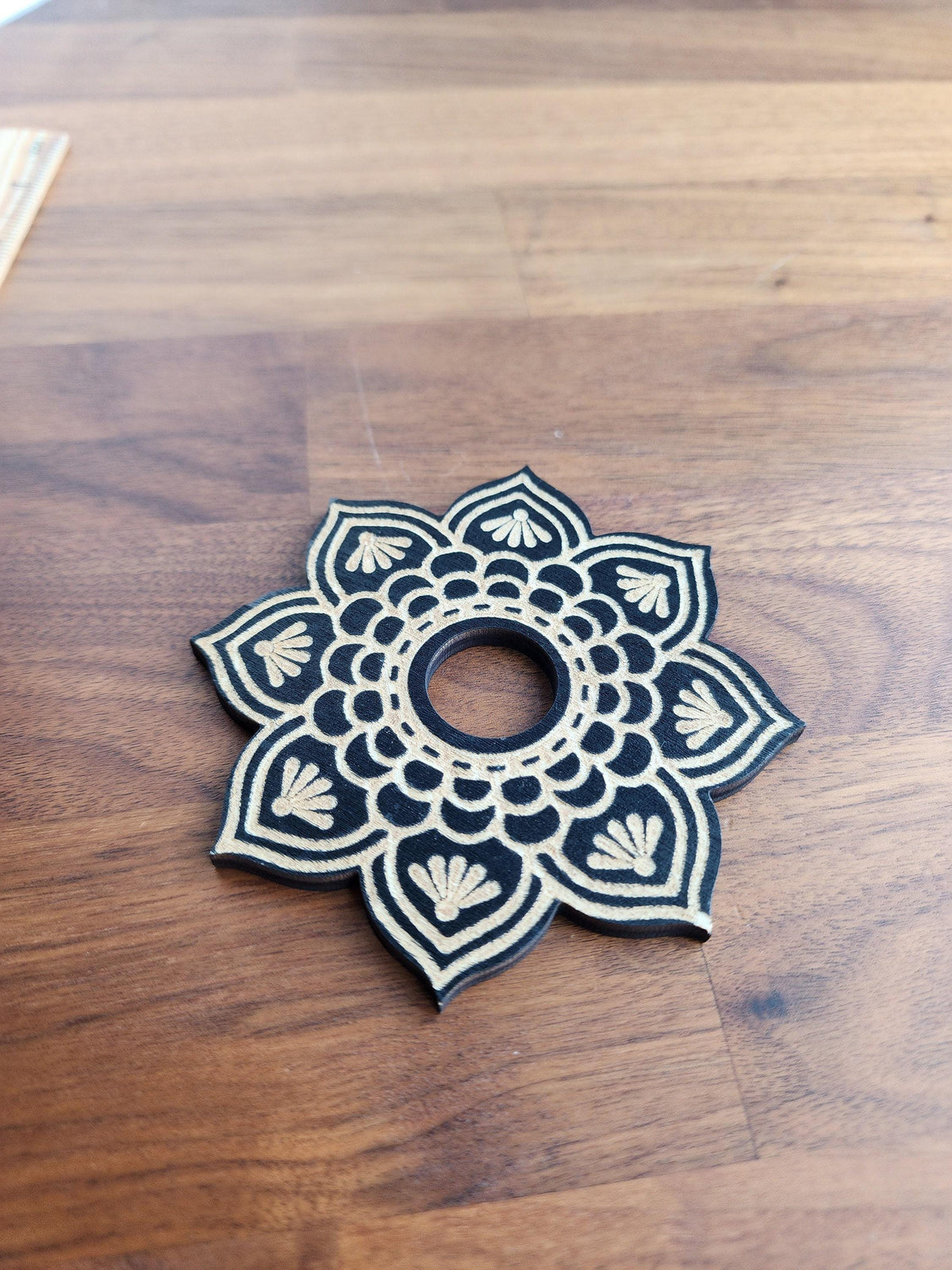 A decorative black and white flower-like pattern on a wooden surface.