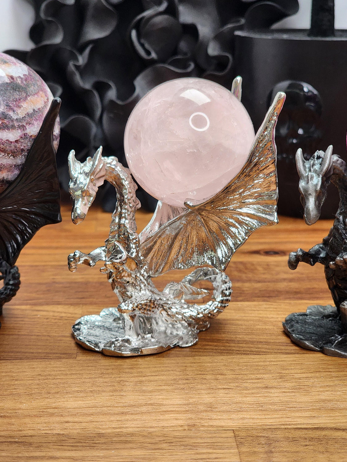 a dragon figurine with a large, round gemstone on its back, placed on a wooden surface.
