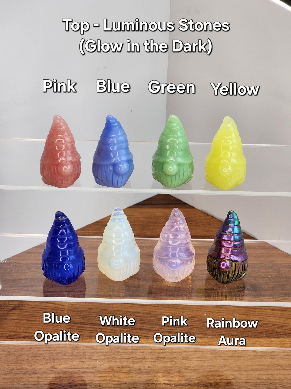a collection of seven colorful gnome-shaped objects, each with a unique color and design, arranged on a wooden surface.