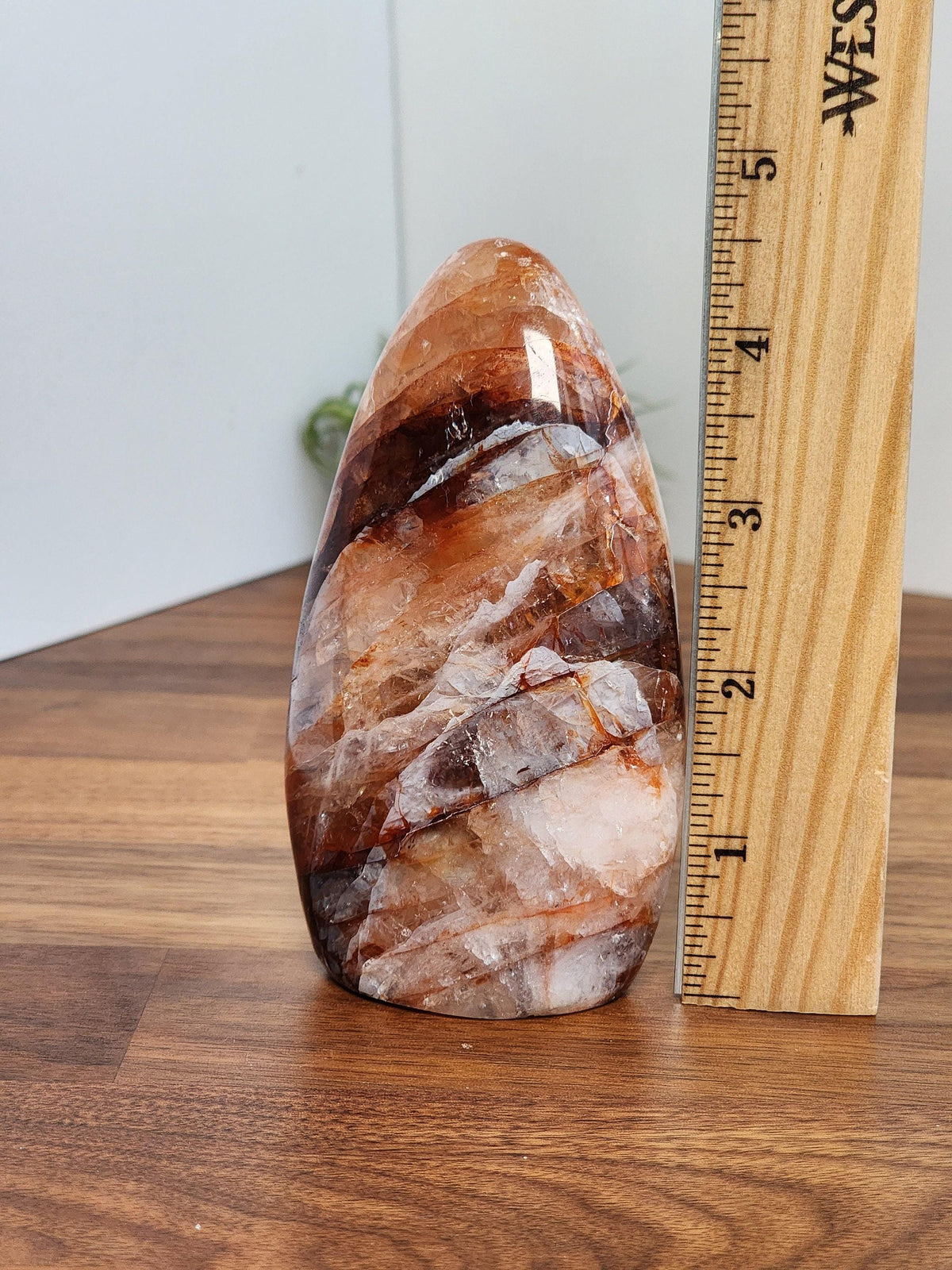 a large, colorful rock formation placed next to a ruler on a wooden surface.