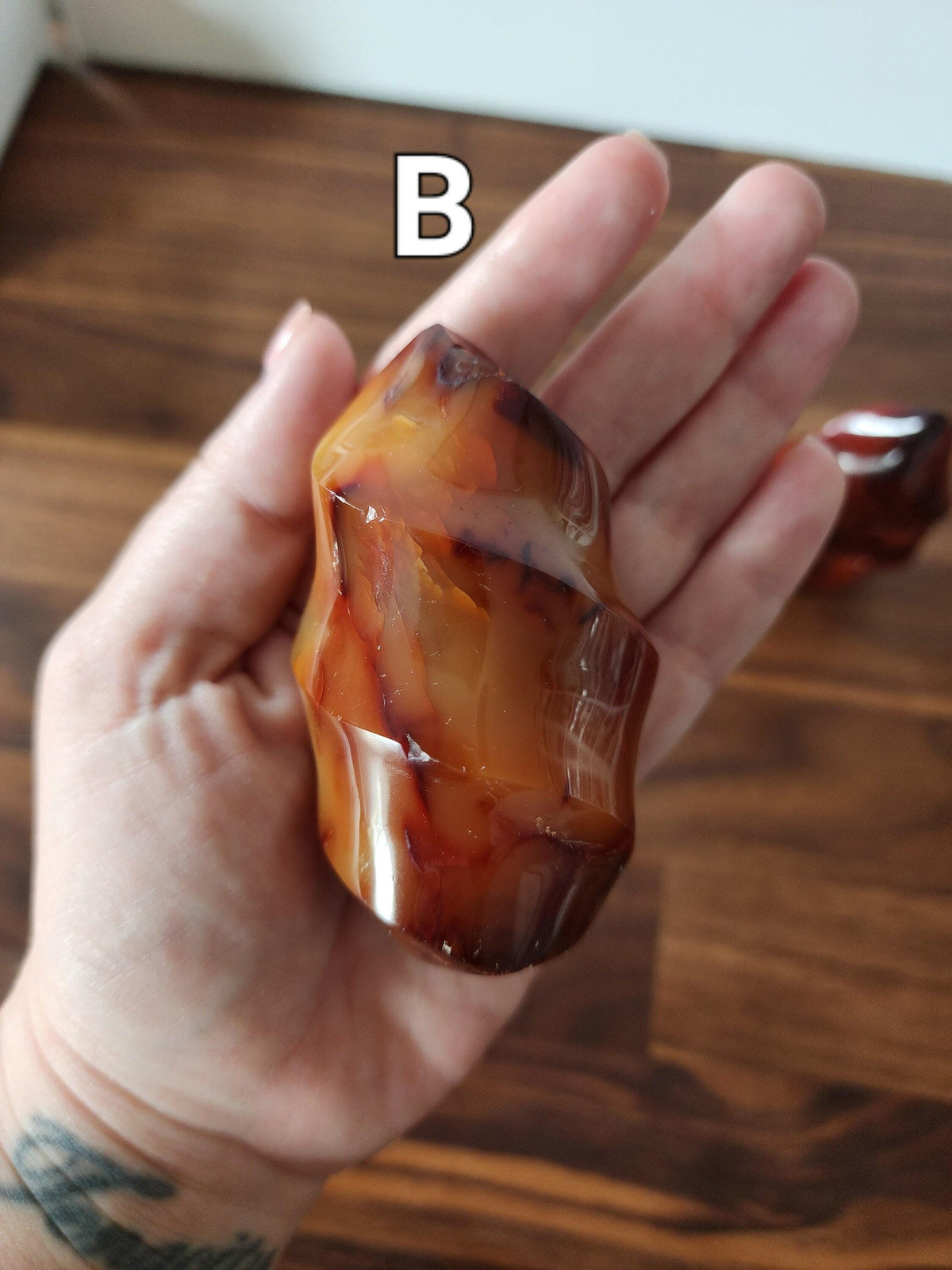 A hand holding a piece of amber-colored stone with a unique, twisted shape.