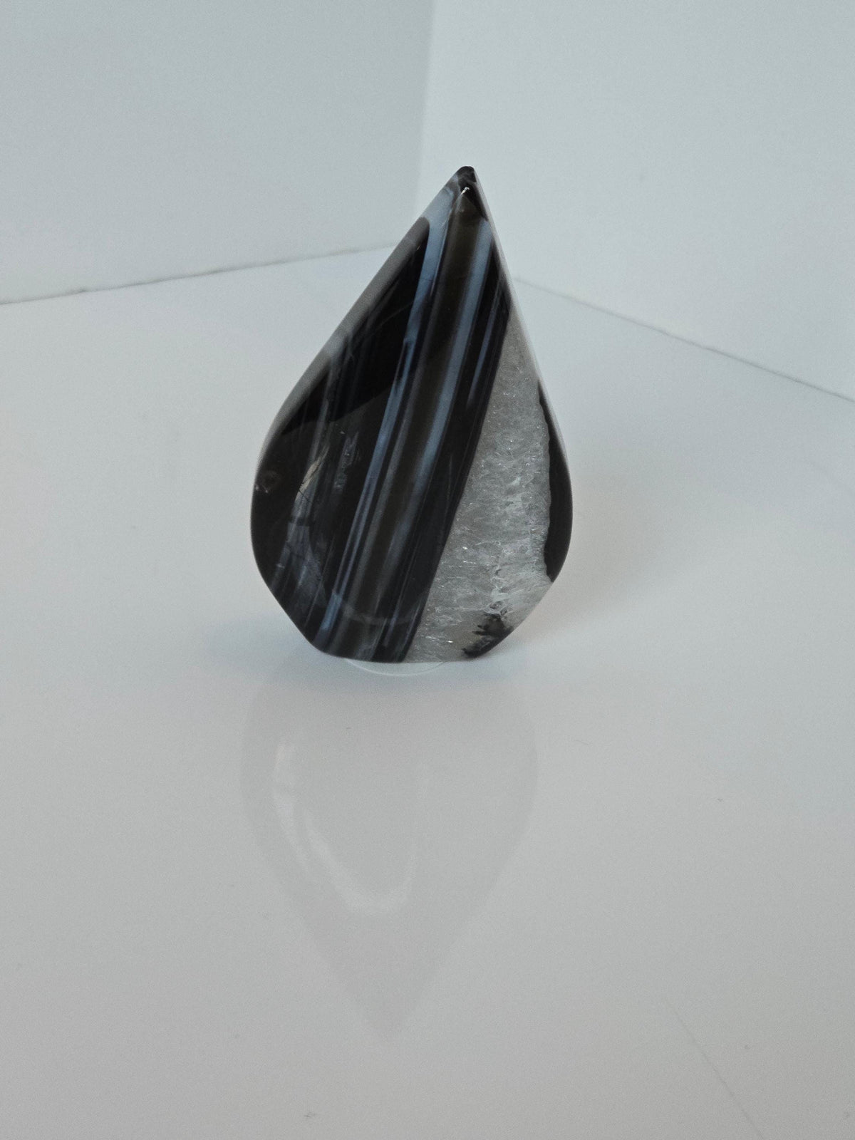 a black and white speckled object, possibly a piece of glass or a stone, sitting on a white surface.