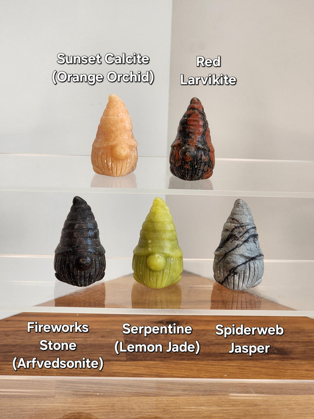 a collection of five unique gnome figurines, each with a distinct color and shape, arranged on a wooden surface.