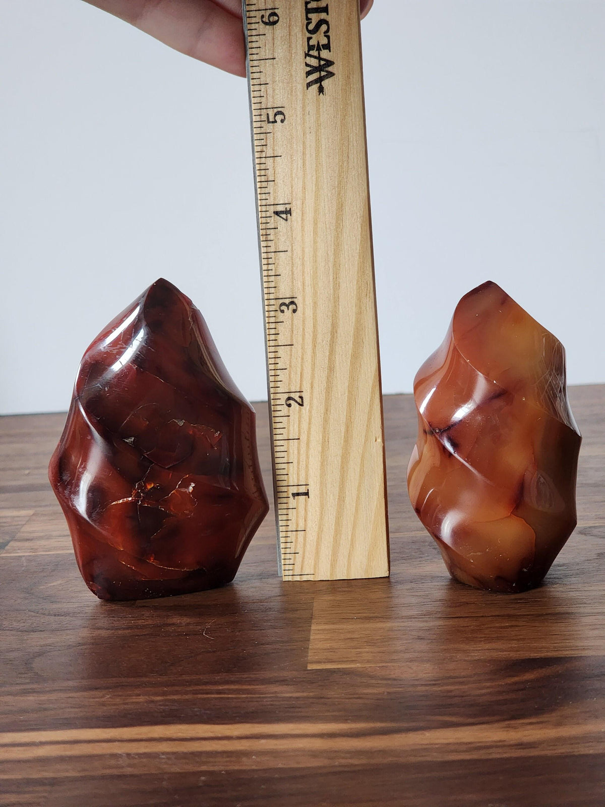 two large, irregularly shaped rocks placed next to a ruler on a wooden surface.