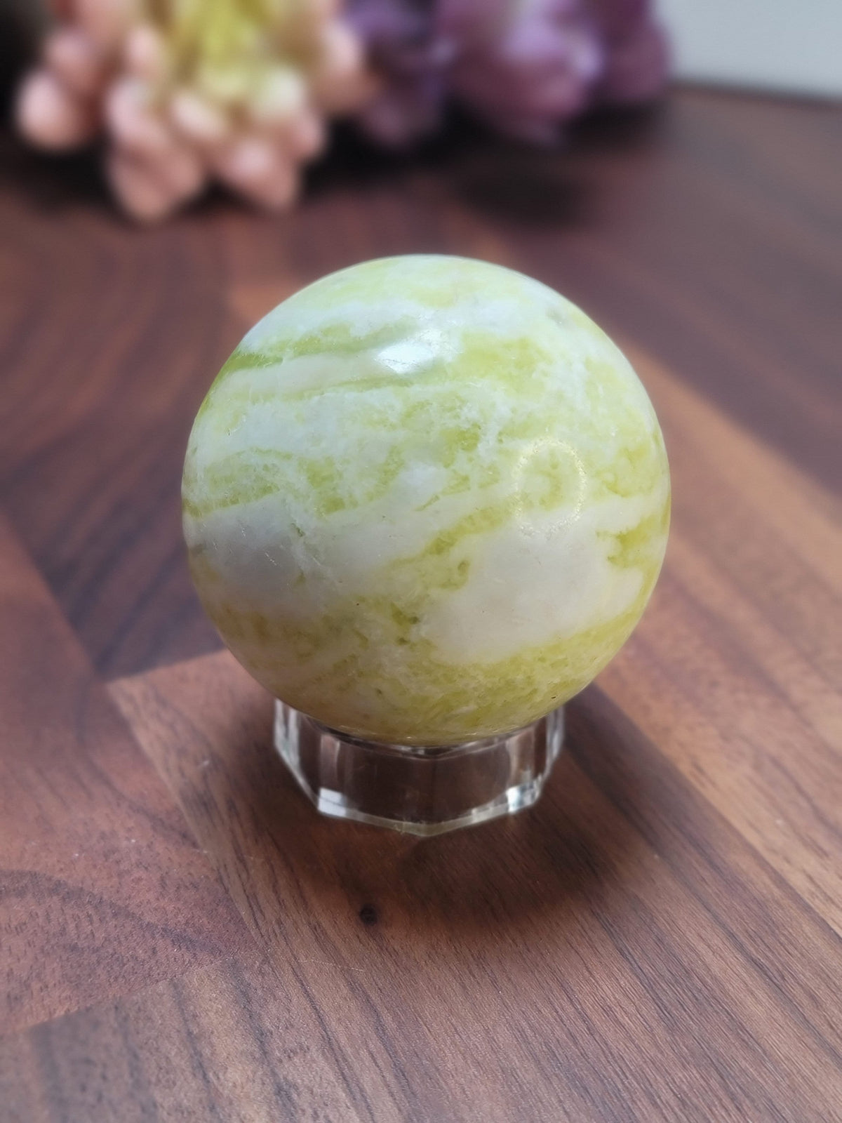May include: A green and white marble sphere on a clear glass stand. The sphere has a swirling pattern of green and white.