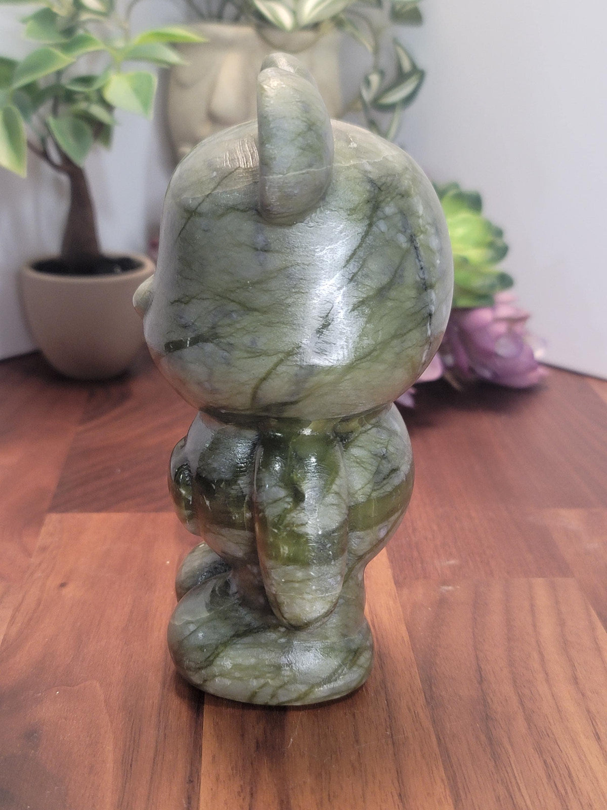a green marble statue of a cat sitting on a wooden surface.