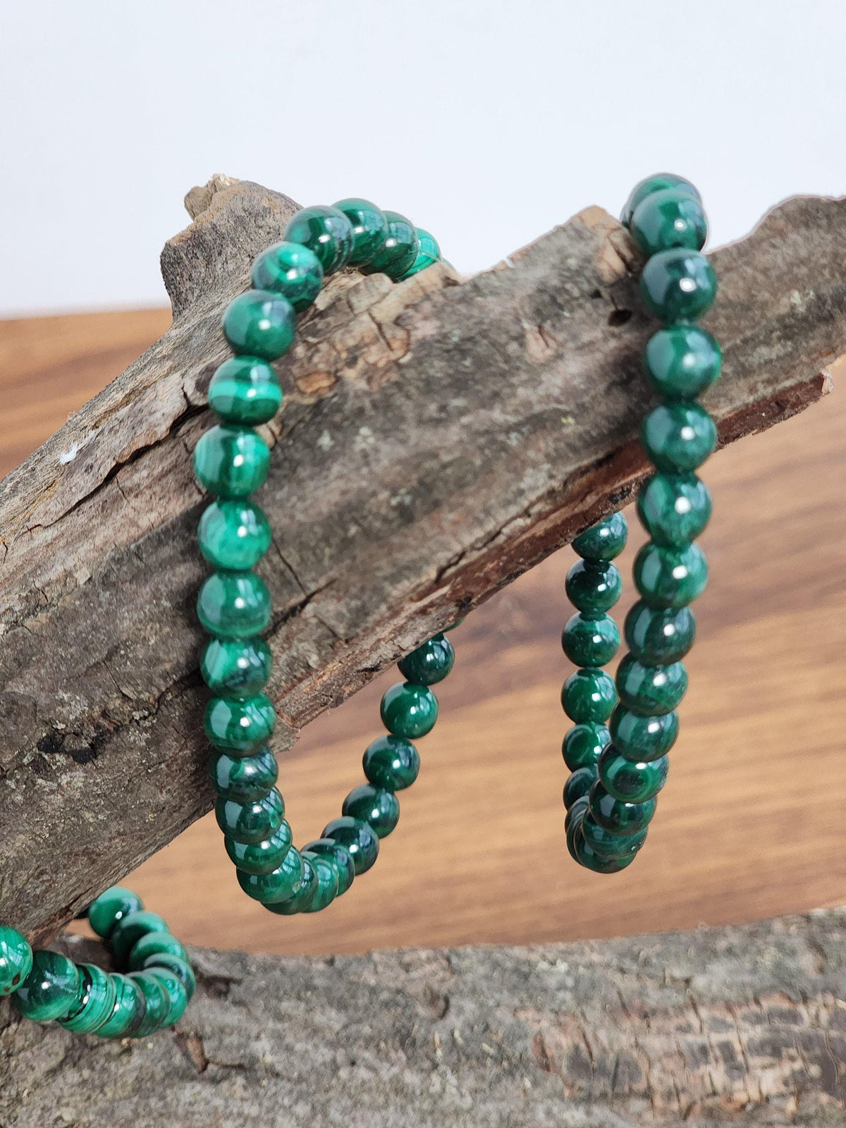 A pair of green malachite bracelets resting on a wooden surface.