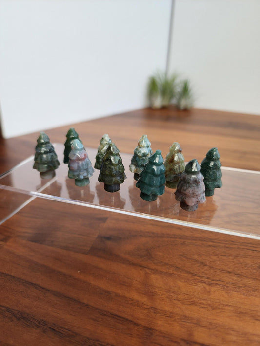 A collection of small, green crystal trees arranged on a wooden surface.