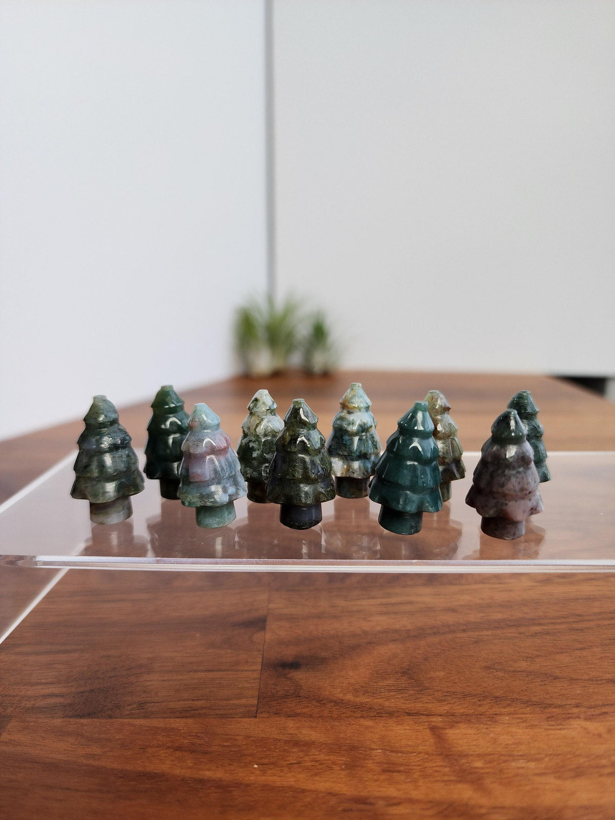 A collection of small, green moss-like figurines resembling trees, arranged on a wooden surface.