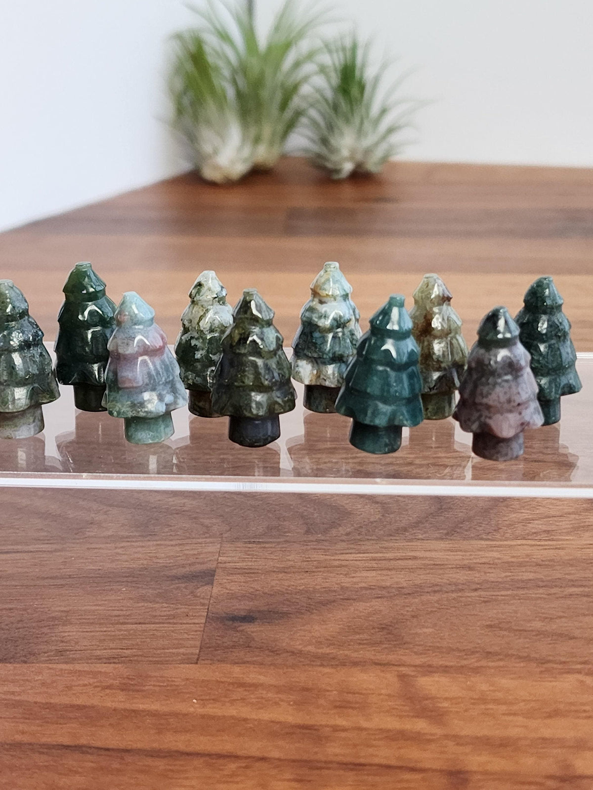 A collection of small, colorful tree-shaped objects, likely made of a material that resembles wood or stone, arranged on a wooden surface.