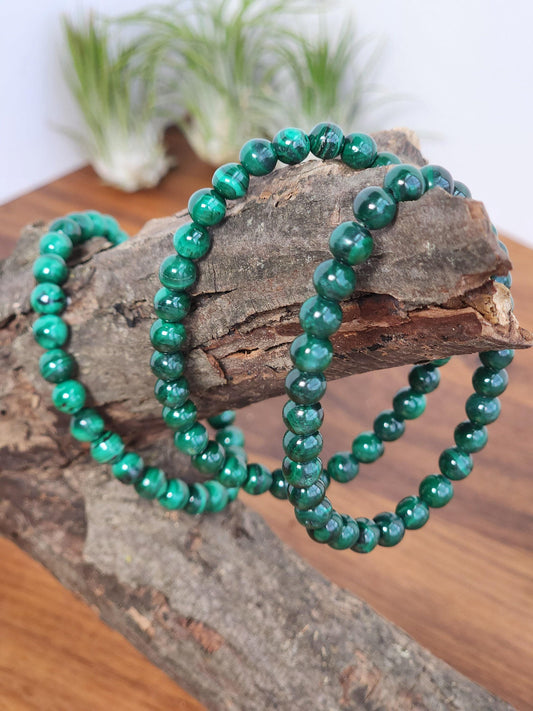 a pair of green malachite bracelets resting on a wooden surface.