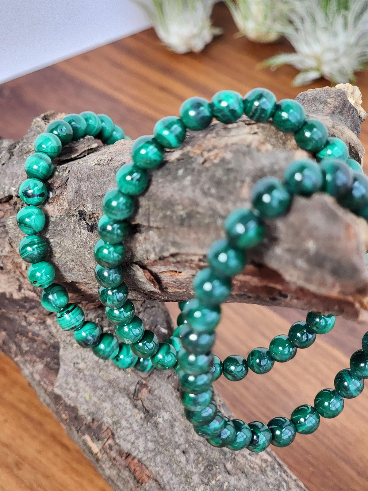 A pair of green malachite bracelets resting on a wooden surface.