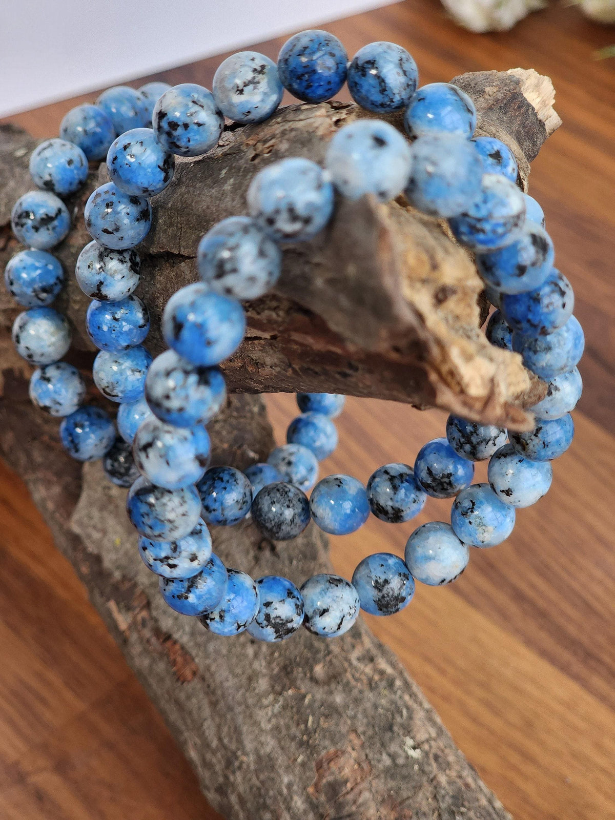 A bracelet made of blue and black stones is displayed on a wooden surface.